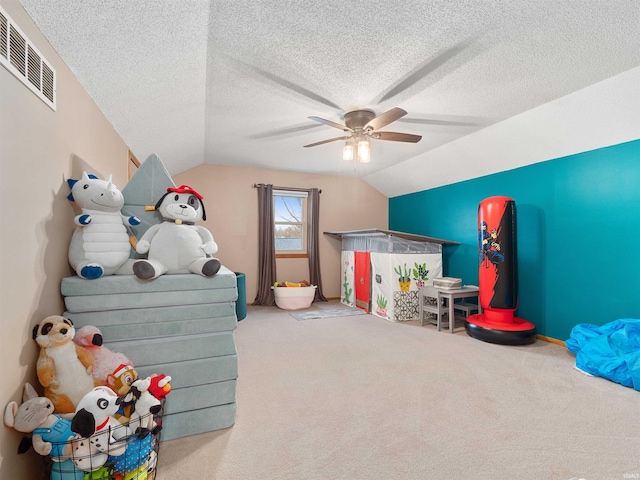 playroom featuring carpet, visible vents, a ceiling fan, vaulted ceiling, and a textured ceiling