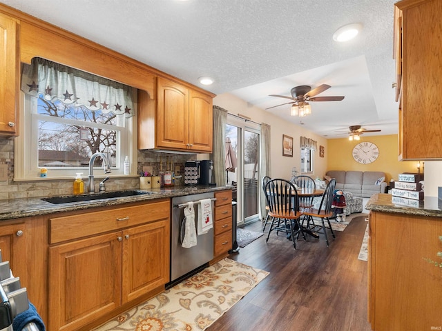 kitchen with dark wood-style flooring, brown cabinets, dishwasher, and a sink