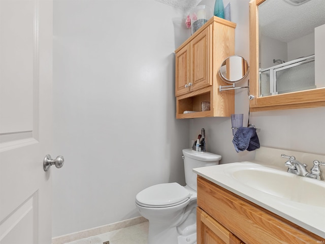 bathroom featuring a textured ceiling, toilet, vanity, baseboards, and a stall shower