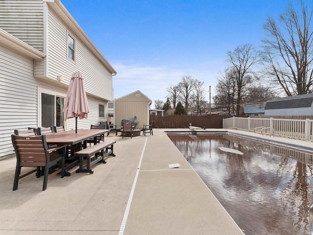 view of patio / terrace featuring a storage shed, a fenced in pool, a fenced backyard, outdoor dining area, and an outdoor structure