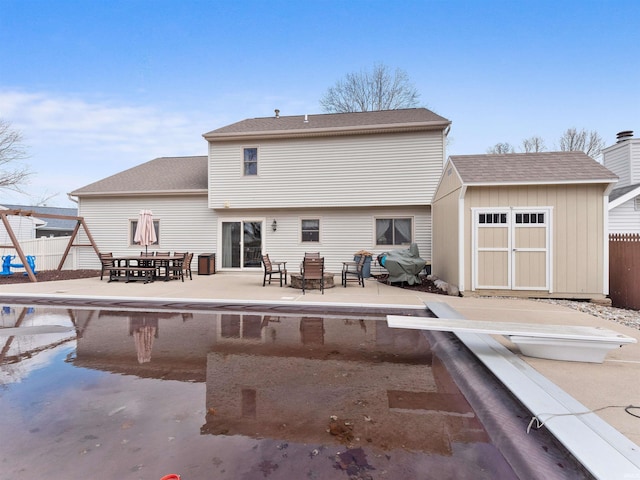 rear view of house featuring a patio area, a shed, fence, and an outbuilding