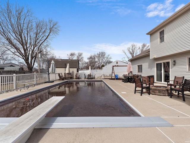 view of swimming pool with an outdoor fire pit, outdoor dining area, a patio area, and a fenced backyard