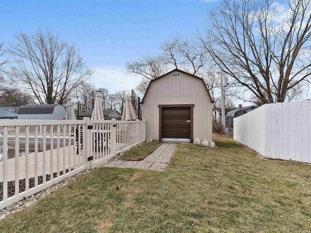 view of barn with driveway, fence, and a yard