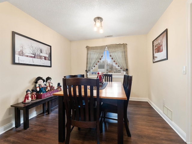 dining space featuring a textured ceiling, dark wood-type flooring, visible vents, and baseboards