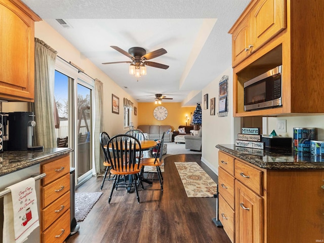 kitchen featuring dark wood-style floors, stainless steel appliances, visible vents, and brown cabinets