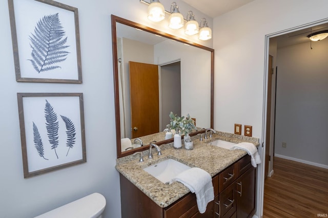 bathroom featuring baseboards, a sink, toilet, and wood finished floors