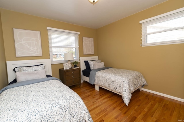 bedroom featuring multiple windows, wood finished floors, and baseboards