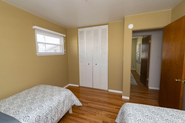 bedroom featuring a closet, baseboards, and wood finished floors