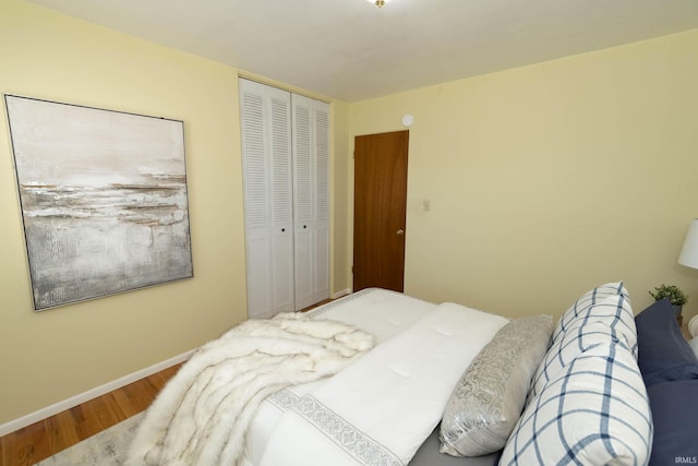 bedroom with a closet, wood finished floors, and baseboards