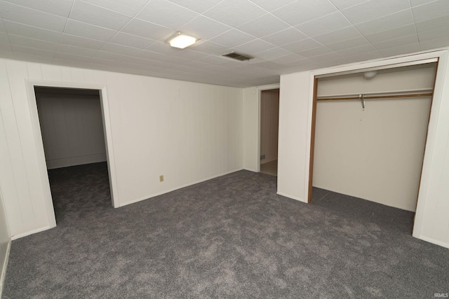 unfurnished bedroom with dark colored carpet, a closet, and visible vents