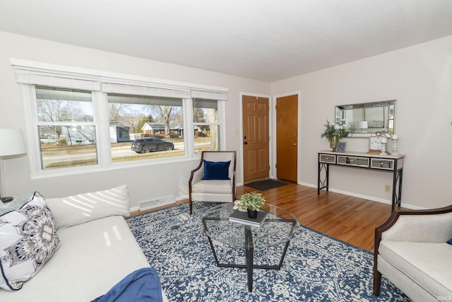 living area with visible vents, baseboards, and wood finished floors