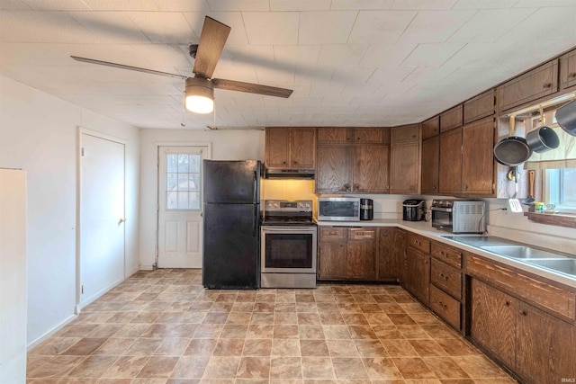 kitchen featuring ceiling fan, under cabinet range hood, stainless steel appliances, baseboards, and light countertops