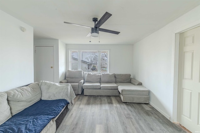 living area featuring ceiling fan, baseboards, and wood finished floors