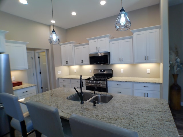 kitchen featuring stainless steel appliances, white cabinets, a sink, and light stone counters