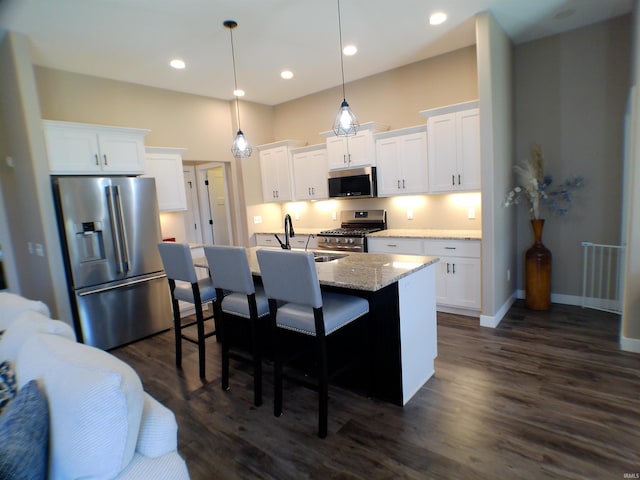 kitchen with an island with sink, dark wood-type flooring, stainless steel appliances, a kitchen bar, and white cabinetry