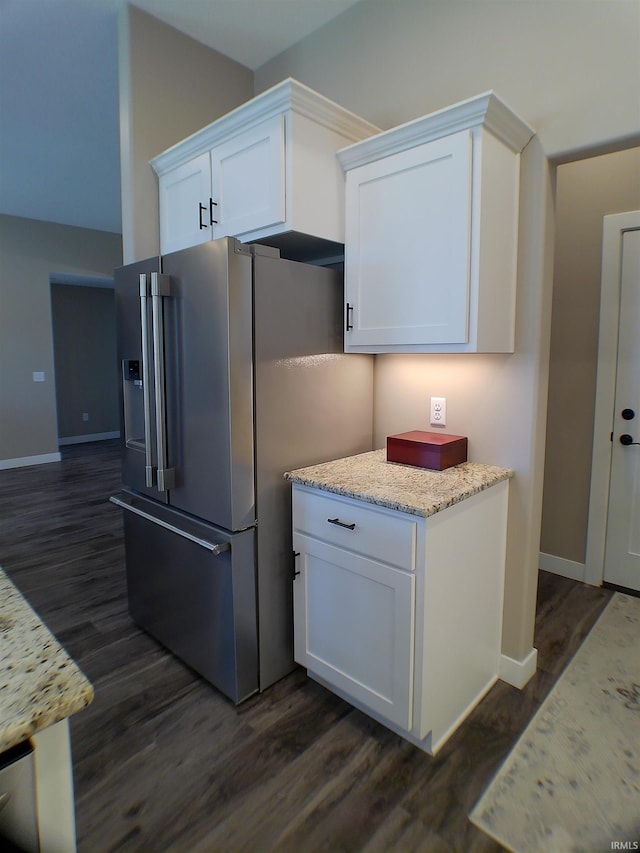 kitchen with dark wood-style flooring, white cabinetry, baseboards, light stone countertops, and stainless steel fridge