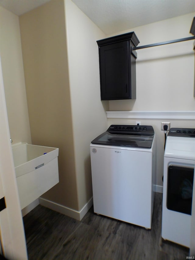 laundry room with washing machine and clothes dryer, cabinet space, dark wood-type flooring, a sink, and baseboards