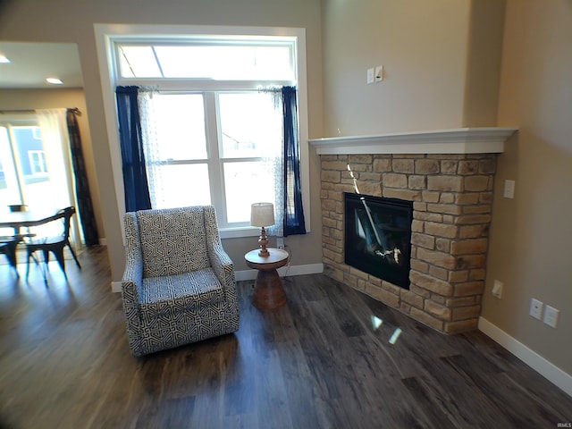 sitting room with a glass covered fireplace, baseboards, and wood finished floors