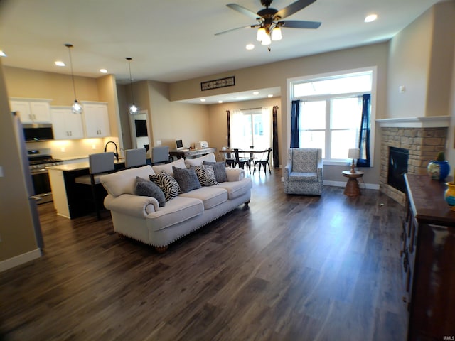 living room with recessed lighting, dark wood-style flooring, a fireplace, and baseboards