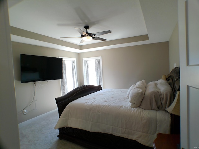 bedroom featuring a ceiling fan, a tray ceiling, and carpet flooring