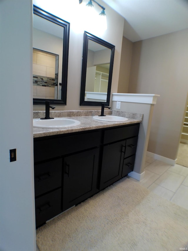 full bath featuring tile patterned flooring, a sink, baseboards, and double vanity