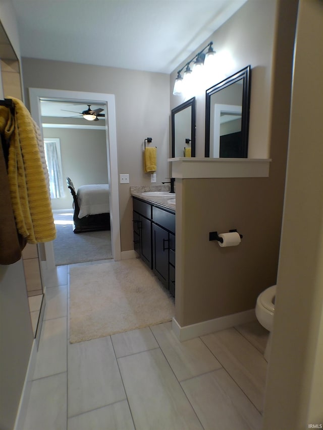 bathroom featuring connected bathroom, toilet, vanity, baseboards, and a ceiling fan