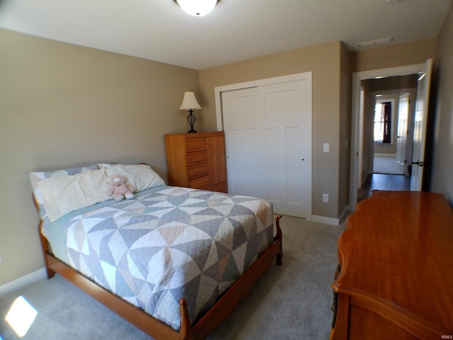 bedroom featuring baseboards, a closet, visible vents, and light colored carpet