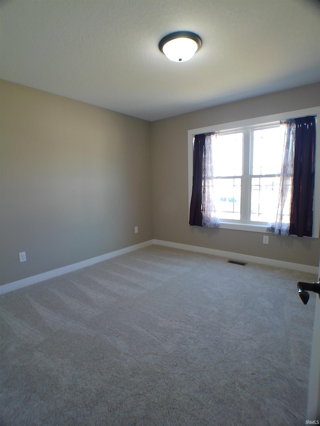 carpeted spare room featuring visible vents and baseboards