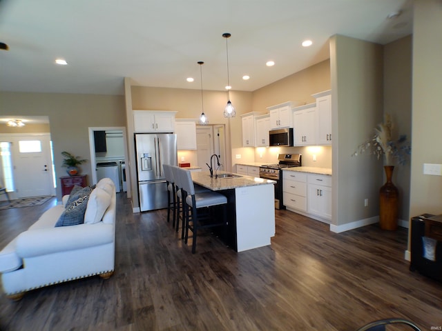 kitchen featuring dark wood-style flooring, a breakfast bar area, stainless steel appliances, white cabinets, and an island with sink