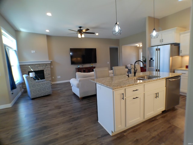 kitchen featuring dark wood-style flooring, a fireplace, appliances with stainless steel finishes, open floor plan, and a sink