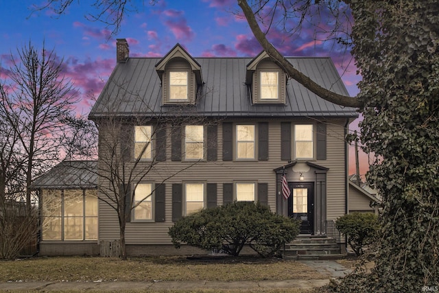 view of front of house featuring a standing seam roof, metal roof, and a chimney