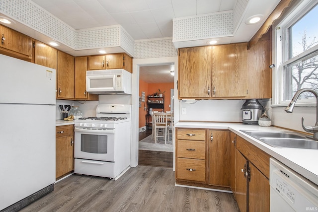 kitchen with white appliances, dark wood-style flooring, a sink, light countertops, and brown cabinetry