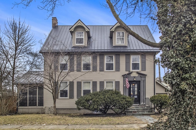 view of front of property with a standing seam roof, metal roof, and a chimney