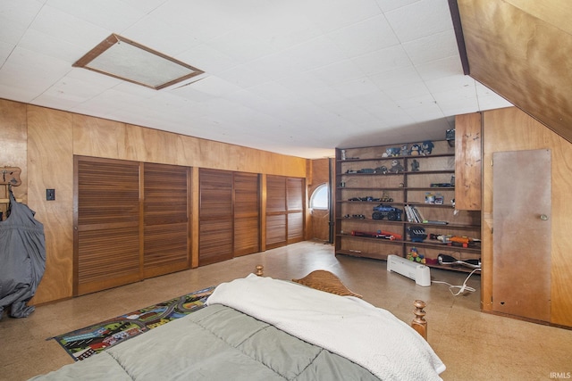 bedroom with attic access, wooden walls, and tile patterned floors