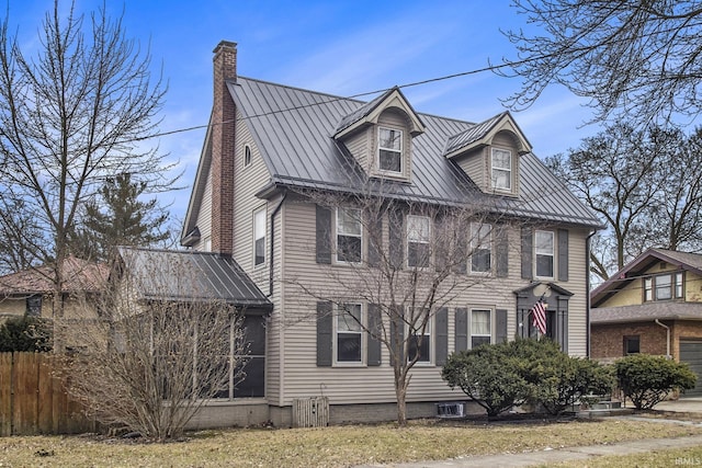 view of front of property featuring a sunroom, a chimney, metal roof, a standing seam roof, and fence