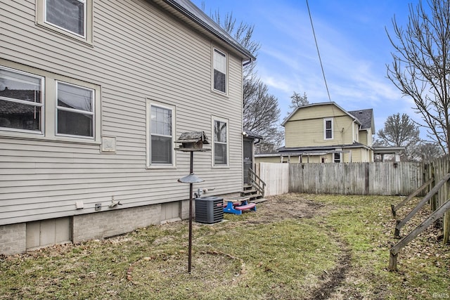 exterior space featuring fence, central AC unit, and a yard