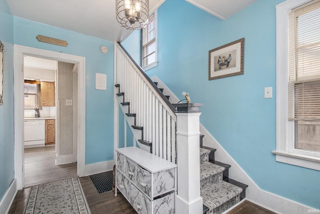 stairway featuring plenty of natural light, wood finished floors, and baseboards