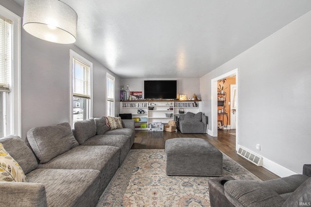 living room with wood finished floors, visible vents, and baseboards