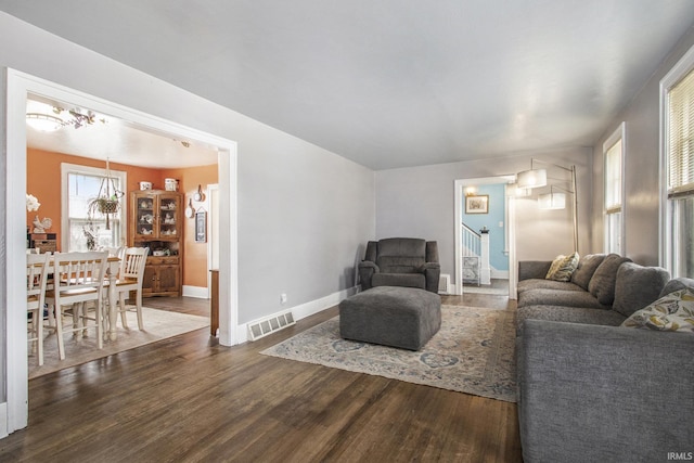 living area with stairway, wood finished floors, visible vents, and baseboards