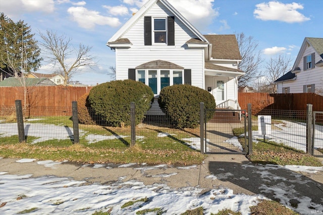 traditional-style house featuring a fenced front yard, a gate, and roof with shingles