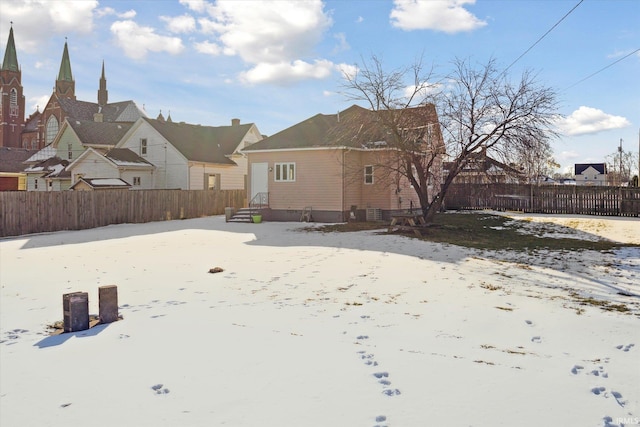 snow covered house featuring fence