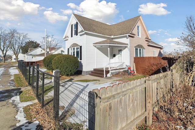 view of front of house featuring a fenced front yard and a shingled roof