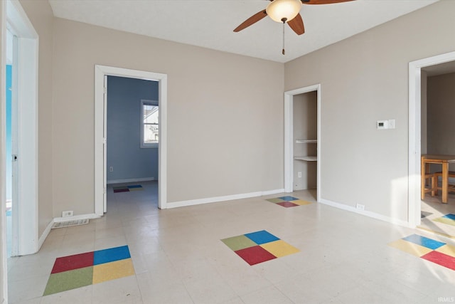 workout room featuring tile patterned floors, a ceiling fan, and baseboards