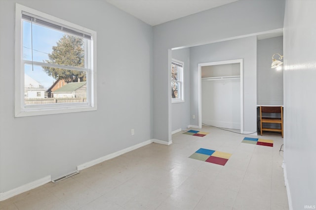 unfurnished bedroom with a closet, visible vents, baseboards, and tile patterned floors