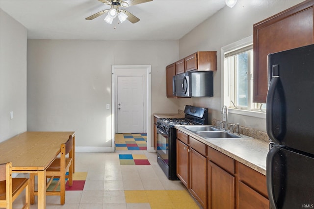 kitchen featuring brown cabinets, black appliances, light floors, and a sink