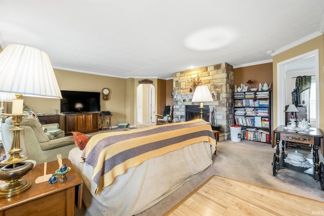 bedroom with ornamental molding, a fireplace, and wood finished floors