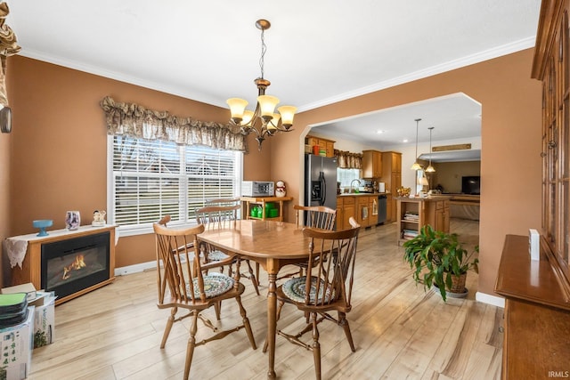 dining area with light wood finished floors, crown molding, baseboards, and a notable chandelier