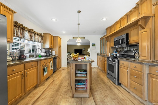 kitchen with dark countertops, light wood-type flooring, stainless steel appliances, and a sink