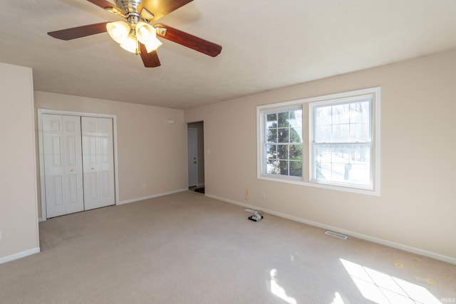 unfurnished bedroom featuring carpet floors, a closet, visible vents, ceiling fan, and baseboards