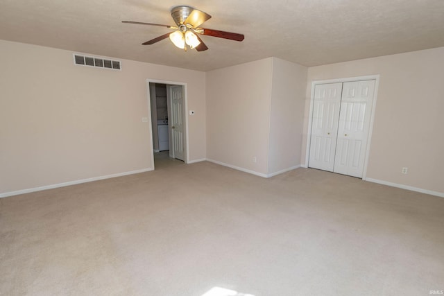 empty room with light colored carpet, visible vents, a textured ceiling, and baseboards